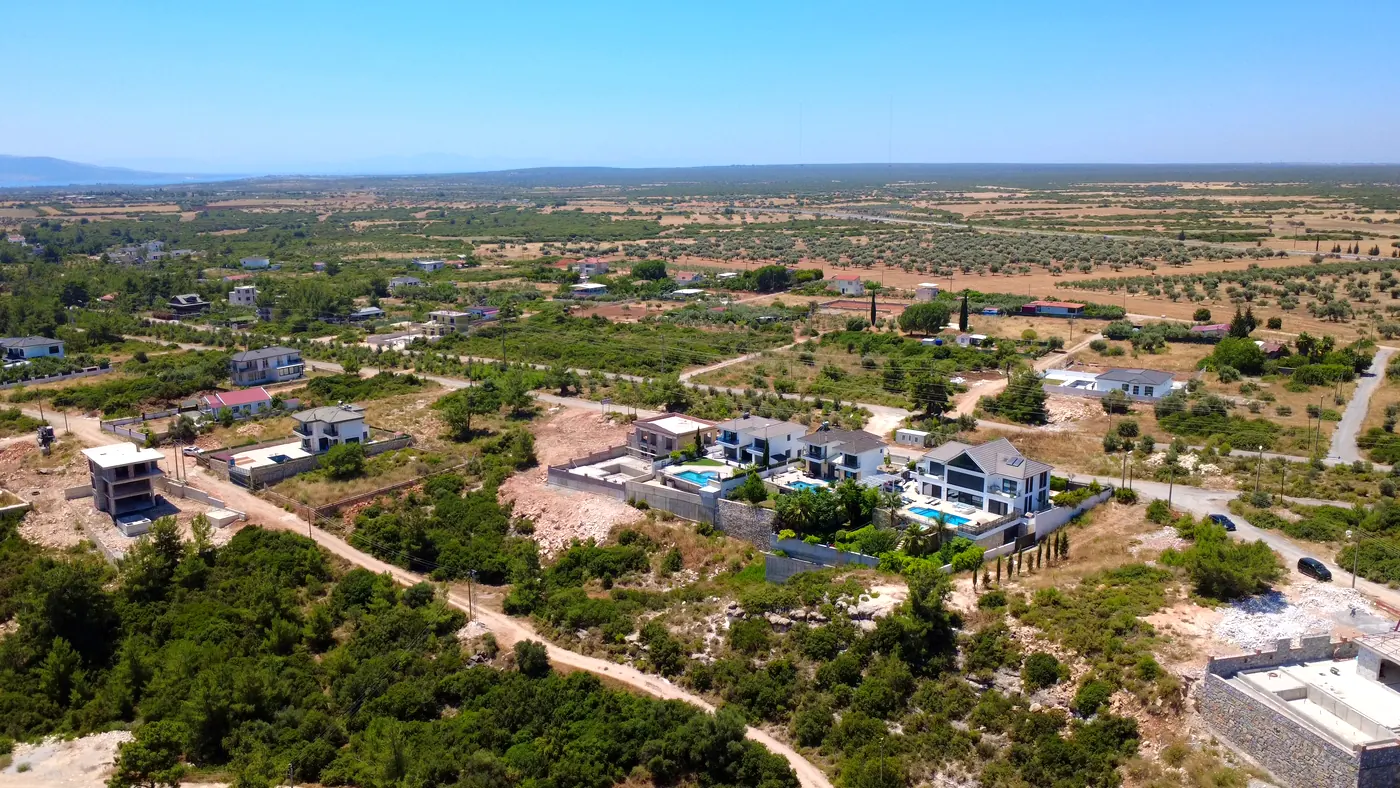 Drone view of modern villas with pools next to olive groves in Seyrantepe, Didim